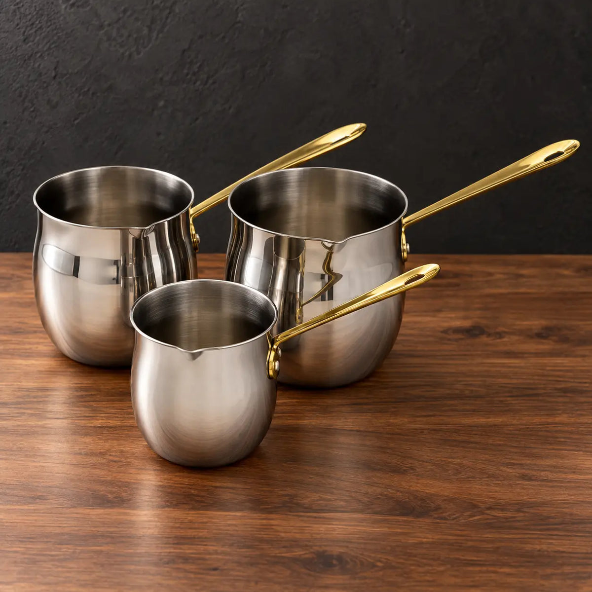 Three double-bottom stainless steel milk cups with gold handles