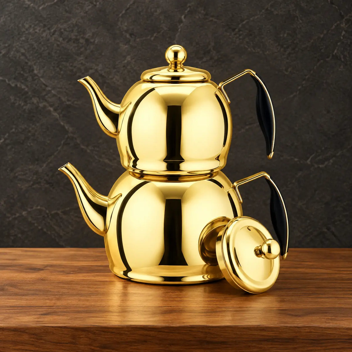Two reflective gold Planet kettles stacked together with black handle grips and a separate round lid