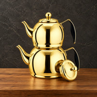 Two reflective gold Planet kettles stacked together with black handle grips and a separate round lid