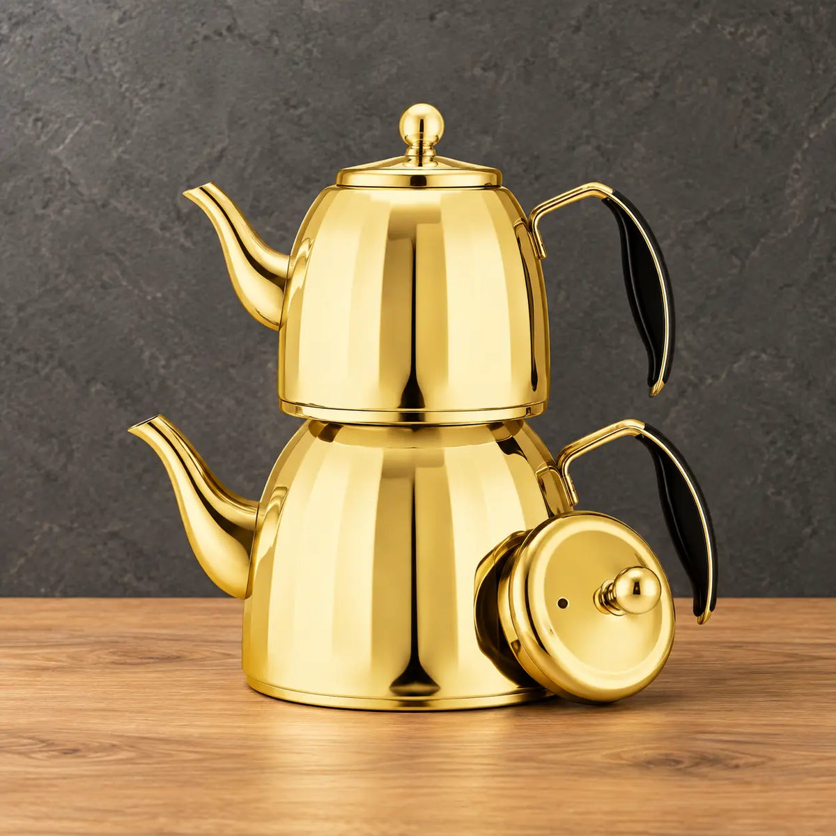 Two gold Star Sparkle teapots with tapered paneled bodies, black handle grips, and a separate lid