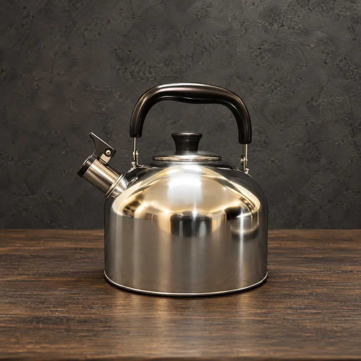 Low rounded Japanese-style silver kettle with a black handle grip, fitted lid, and whistle spout