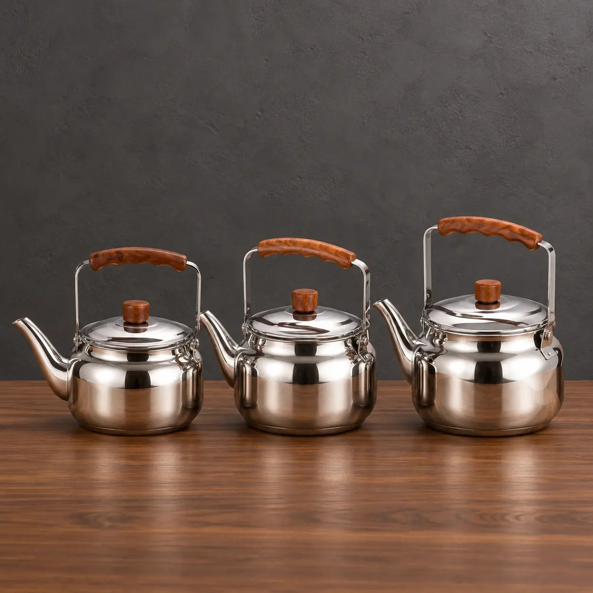 Three polished Lily teapots in graduated sizes with brown handle grips displayed above a green product box