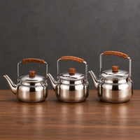 Three polished Lily teapots in graduated sizes with brown handle grips displayed above a green product box