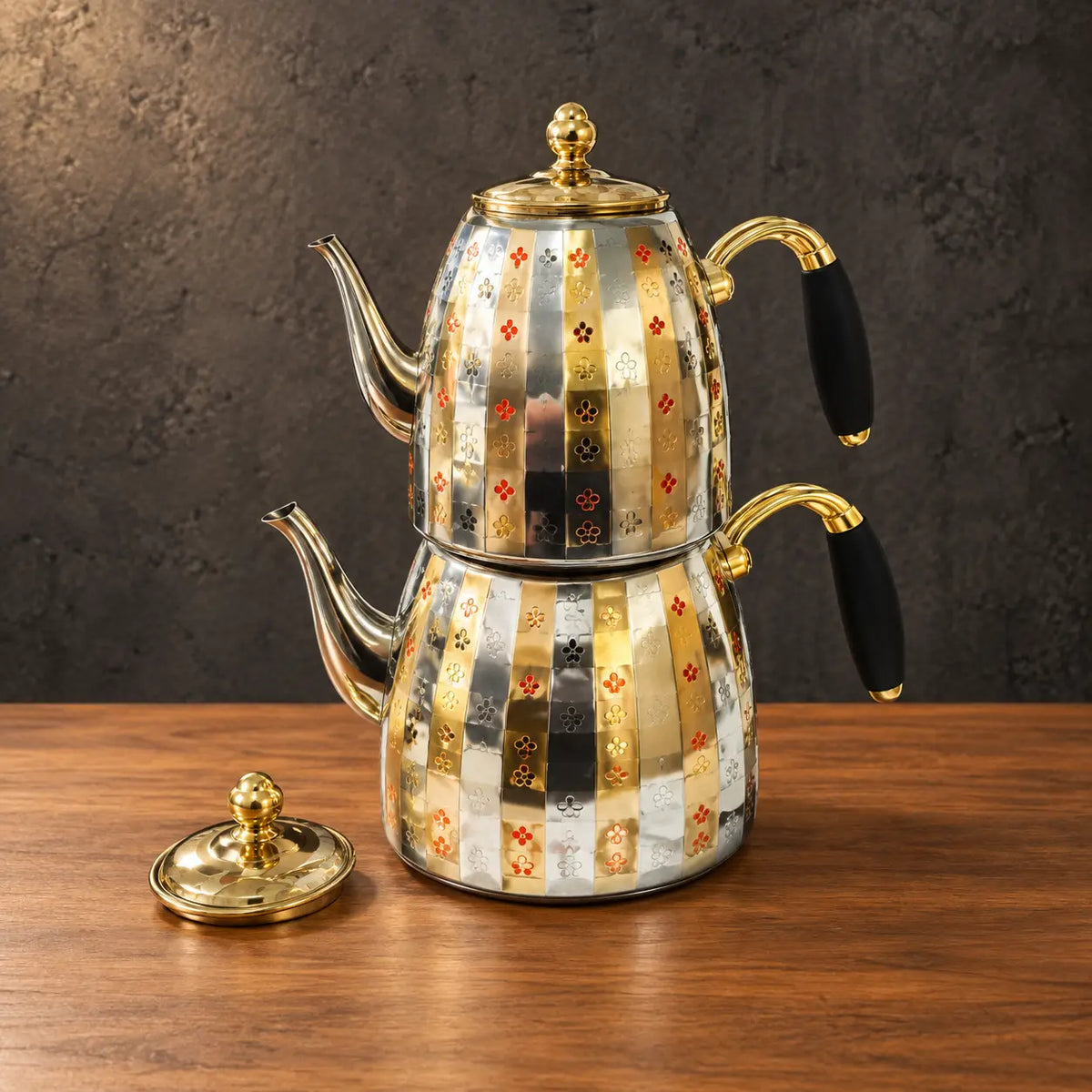 Patterned stainless steel nesting kettle set with gold-tone accents, black side-handle grips, and a separate lid
