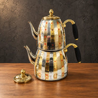 Patterned stainless steel nesting kettle set with gold-tone accents, black side-handle grips, and a separate lid