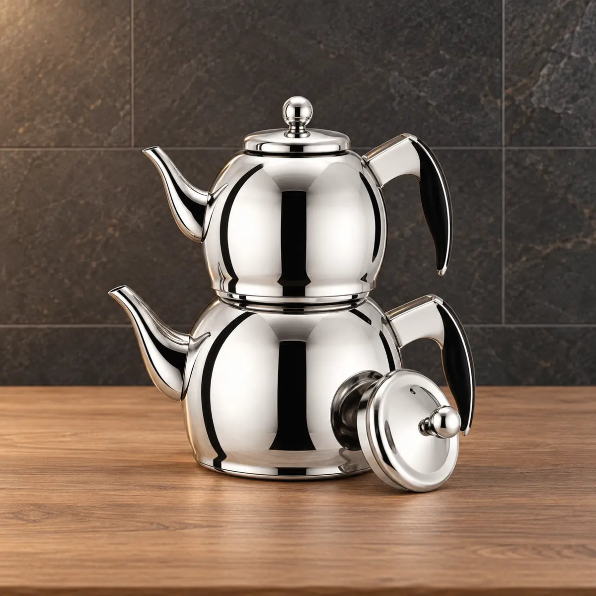 Two polished silver Planet kettles stacked together with black handle grips and a separate round lid