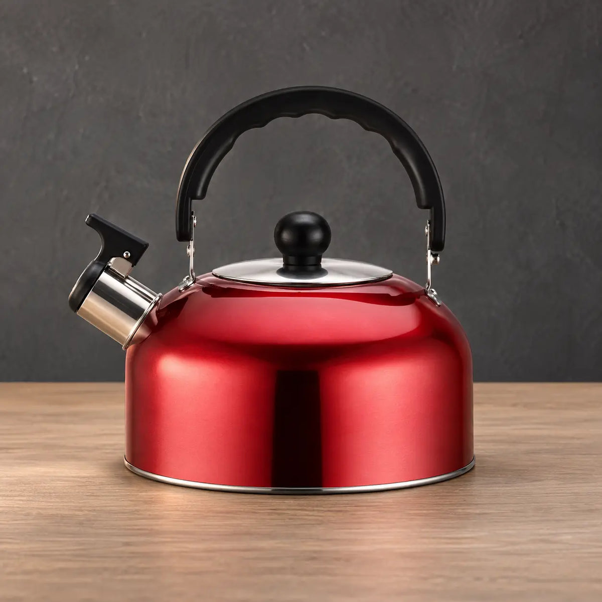 Red thin whistling teapot with a low wide body, black arched handle, black lid knob, and polished lower edge