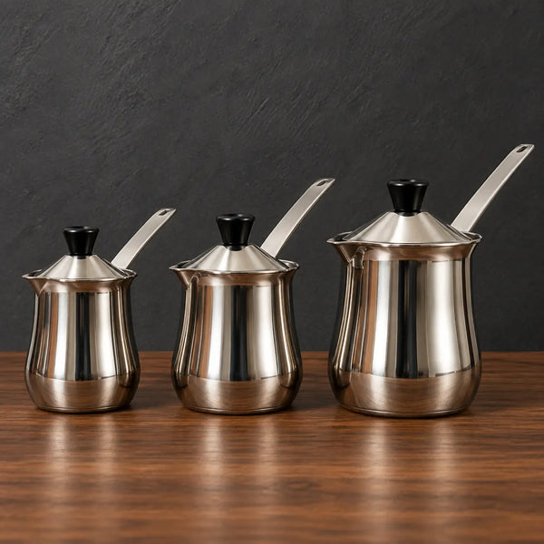 Three polished stainless steel milk cups with fitted lids and metal handles